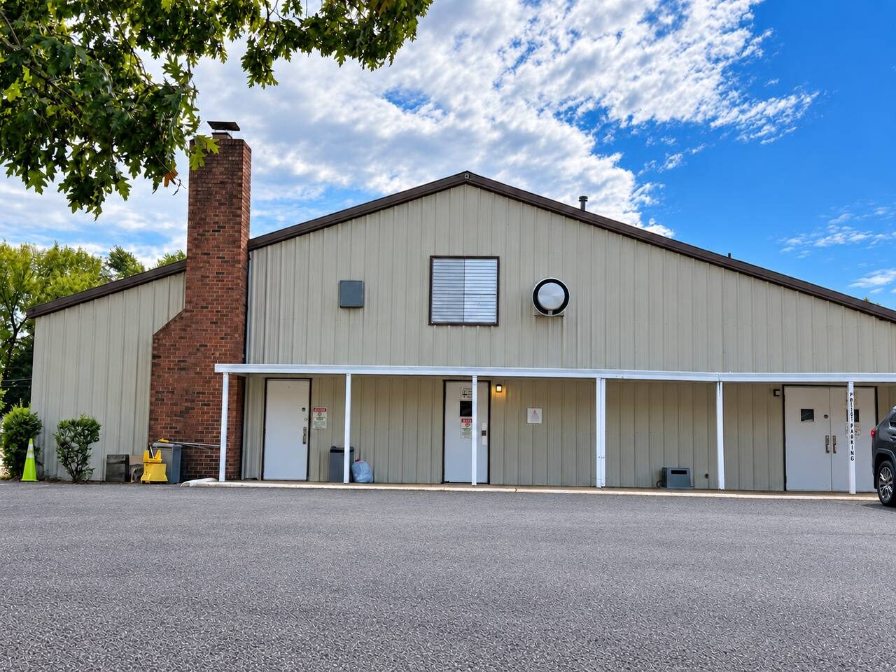 Exterior of the Debre Enqu Beata LeMariam event hall at 2210 Carter St, Richmond, VA, with a covered walkway and three entrance doors facing the parking lot